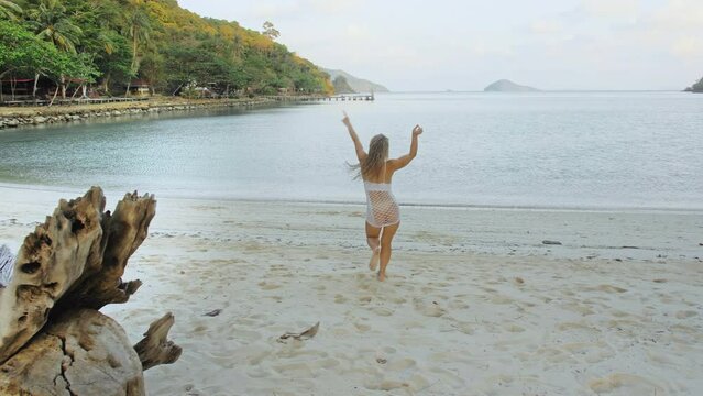 The sexy vibrant young lady is posing on a tree. The woman is having fun on an island vacation. The licentious woman provocative fervently twists her buttocks.