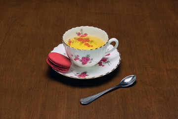 A cup of tea with a single macaron.