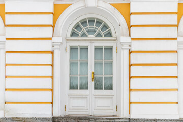Old white wooden door in yellow wall, background texture
