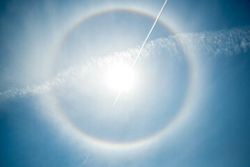 An airplane leaves a vapor trial thought the suns corona.