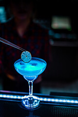 woman bartender hand at the bar or pub to prepare cocktail Blue Lagoon