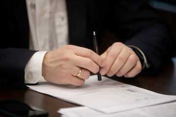 Businessman hand close up writing with pen on the table