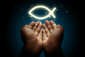 Hand with a glowing ichthys symbol. Christian religious theme concept.