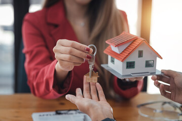 Real estate agent giving house key to the client after signing the real estate contract. Home and real estate trading concept.