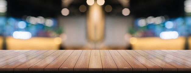 Empty wooden table top with lights bokeh on blur restaurant background.