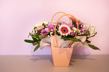 A composition of flowers in a festive box stands on the stairs with lighting. A gift for a beloved woman