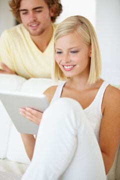 Using Touchscreen Technology. A Beautiful Young Woman Using A Tablet As Her Boyfriend Watches From Over Her Shoulder.