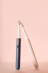 Two new modern ultrasonic toothbrushes. Dental care supplies on pink pastel background. Oral hygiene, dental and gum health, healthy teeth. Dental products Ultrasonic vibration toothbrush.