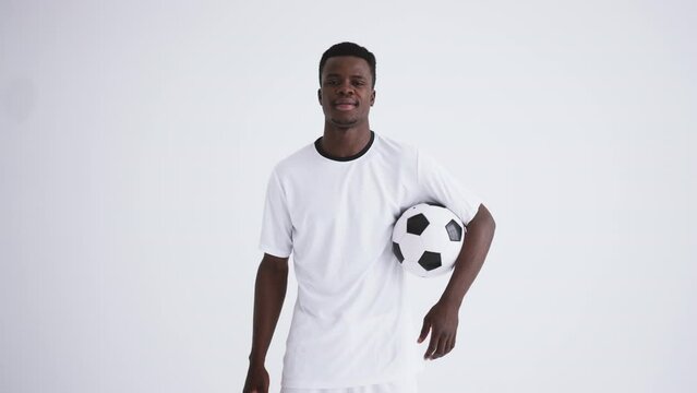 portrait of african-american football player in white background, young sportsman is holding ball