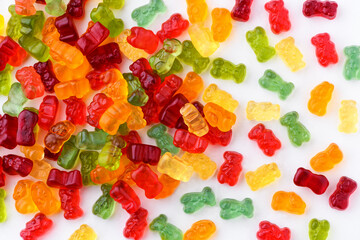 Small gummy bears are scattered on a white background