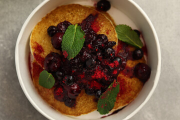Pancakes with berries and mint. Healthy food delivery concept. Restaurant dish in eco paper boxes on gray background. Close up. Top view. 