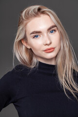 Portrait of a young blonde woman on dark background