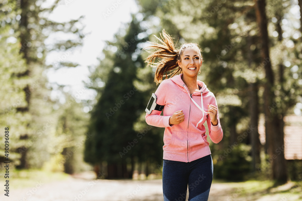 Wall mural Woman Running Along A Sunny Forest Trail