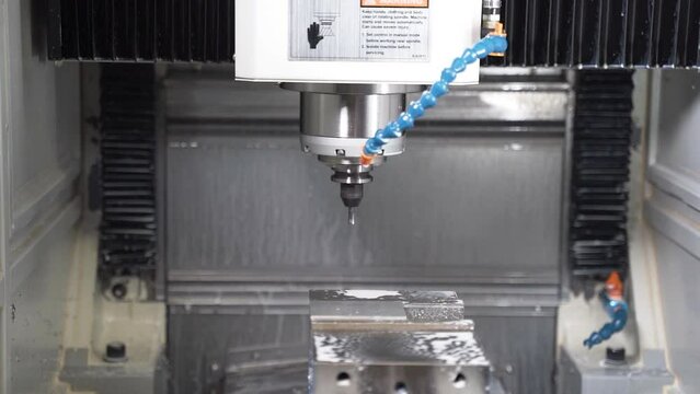 Automatic CNC machine starting drilling, cooled by a cutting fluid.