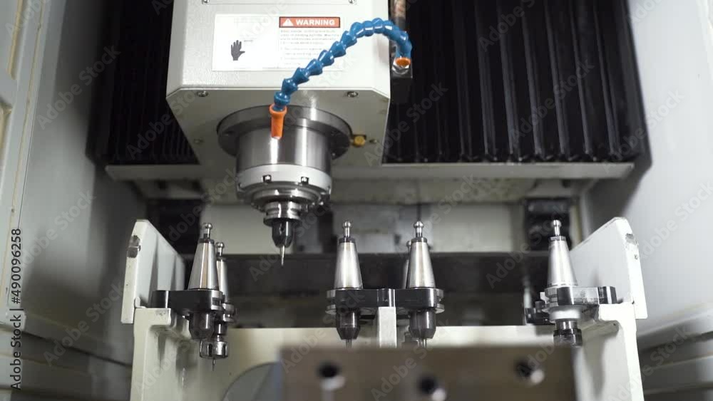 Aufkleber cnc machine selecting and inserting a detachable drill from a set.