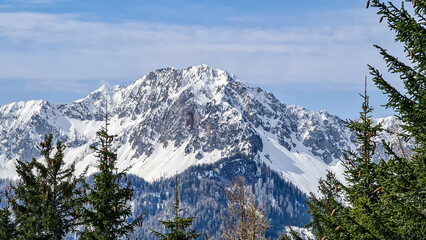 Scenic view of snow capped mountain peaks of Karawanks from Sinacher Gupf in Carinthia, Austria. Mount Hochstuhl (Stol) is visible through dense forest in early spring. Rosental on sunny day. Freedom