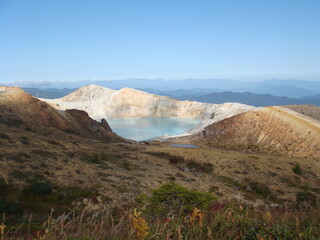 Beautiful toxic and acidic volcanic caldera lake with emerald green water in Yugama, Kusatsu, Gunma...
