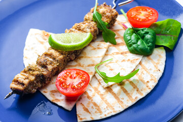 herbal meat skewer  with pita bread, tomatoes and lime