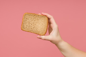 a slice of bread in a female hand on a colored background