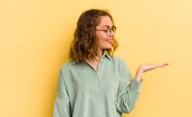young pretty woman feeling happy and smiling casually, looking to an object or concept held on the...