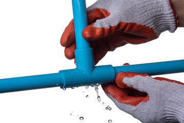 Man's hand holding blue pvc plastic pipe with a broken connection and water pouring out isolated on...