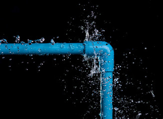 leaked and splash water from pvc plastic pipe over a black background.