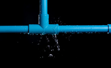 leaked and splash water from pvc plastic pipe over a black background. - obrazy, fototapety, plakaty
