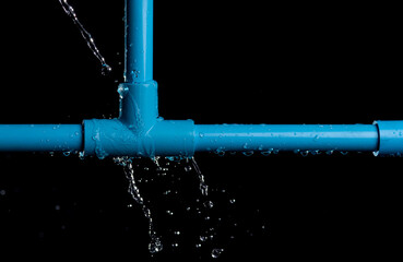 leaked and splash water from pvc plastic pipe over a black background.