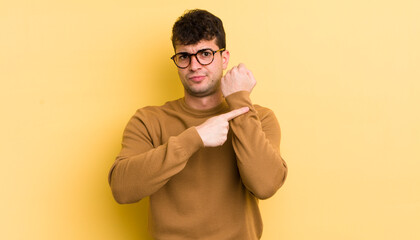 young handsome man looking impatient and angry, pointing at watch, asking for punctuality, wants to...