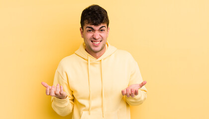 young handsome man feeling clueless and confused, not sure which choice or option to pick, wondering