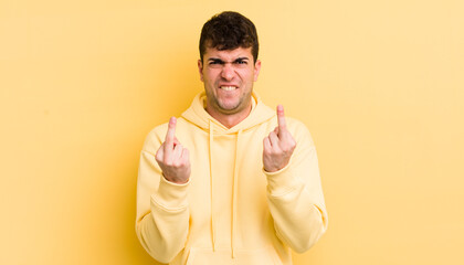 young handsome man feeling provocative, aggressive and obscene, flipping the middle finger, with a...