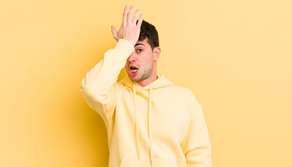 young handsome man raising palm to forehead thinking oops, after making a stupid mistake or...