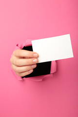 Female hand with gift box punching through the pink paper