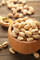Pile of Pistachios on wooden bowl, pistachios on grey wooden background. Vetical photo.