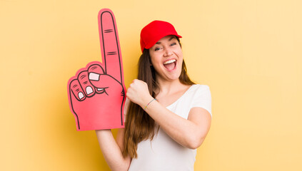 young pretty woman feeling happy and facing a challenge or celebrating. number one hand concept