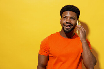 Young man of African American ethnicity 20s wear orange t-shirt talk speak on mobile cell phone...