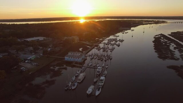 Aerial of Lady's Island South Carolina at sunset with marina, boats, bridge, and Beaufort SC orbiting counter-clockwise drone shot