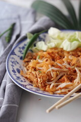 Thai food Pad Thai (national dish) served in a Chinese-style patterned bowl. Place it on a white table.