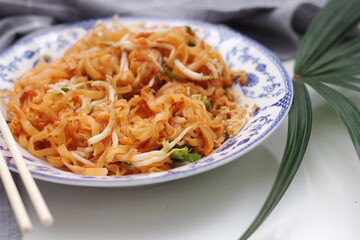 Thai food Pad Thai (national dish) served in a Chinese-style patterned bowl. Place it on a white table.