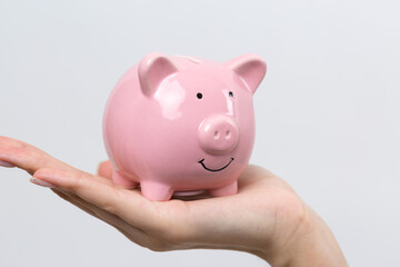 3d pink piggy bank in the beautiful hands of a girl..Close-up photo on a white background.