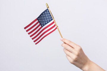 A beautiful female hand holds an American flag on a white background.