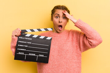 young pretty woman looking happy, astonished and surprised. cinema clapper concept