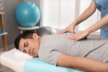 Orthopedist massaging man's back in clinic, closeup. Scoliosis treatment
