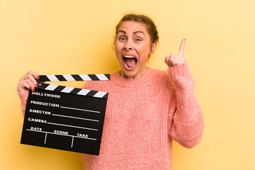 young pretty woman feeling like a happy and excited genius after realizing an idea. cinema clapper...
