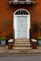 Close up of a front door on a town house with 2 potted plants either side. Home, first timer buyer, new house concept - obrazy, fototapety, plakaty