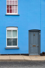 Close up of a blue wooden front door on a bright blue painted house