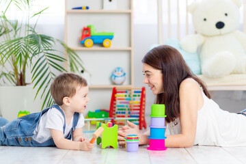 mom and baby boy play at home with educational toys in the children's room. A happy, loving family.