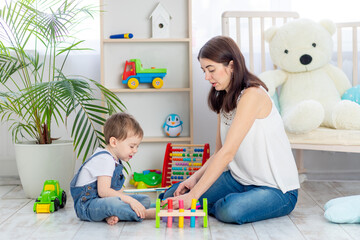 mom plays with the child at home in the educational toys in the children's room. A happy, loving family.