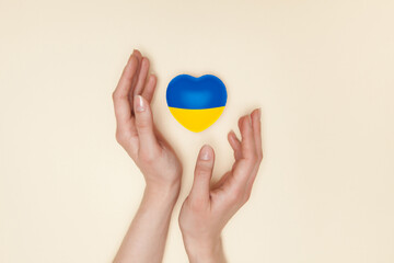 Heart with print the national flag of ukraine in female hands. Flat lay. Copy space.