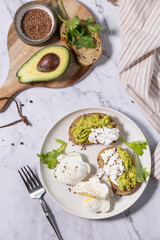Easter breakfast or brunch. Delicious breakfast or snack - poached egg and cream cheese toast whole grain rye bread, avocado on a marble tabletop. Top view flat lay.